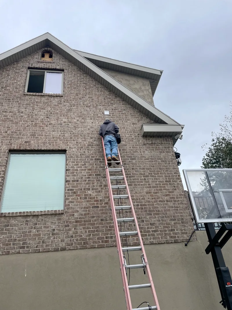 Technician on a ladder at an exterior dryer vent