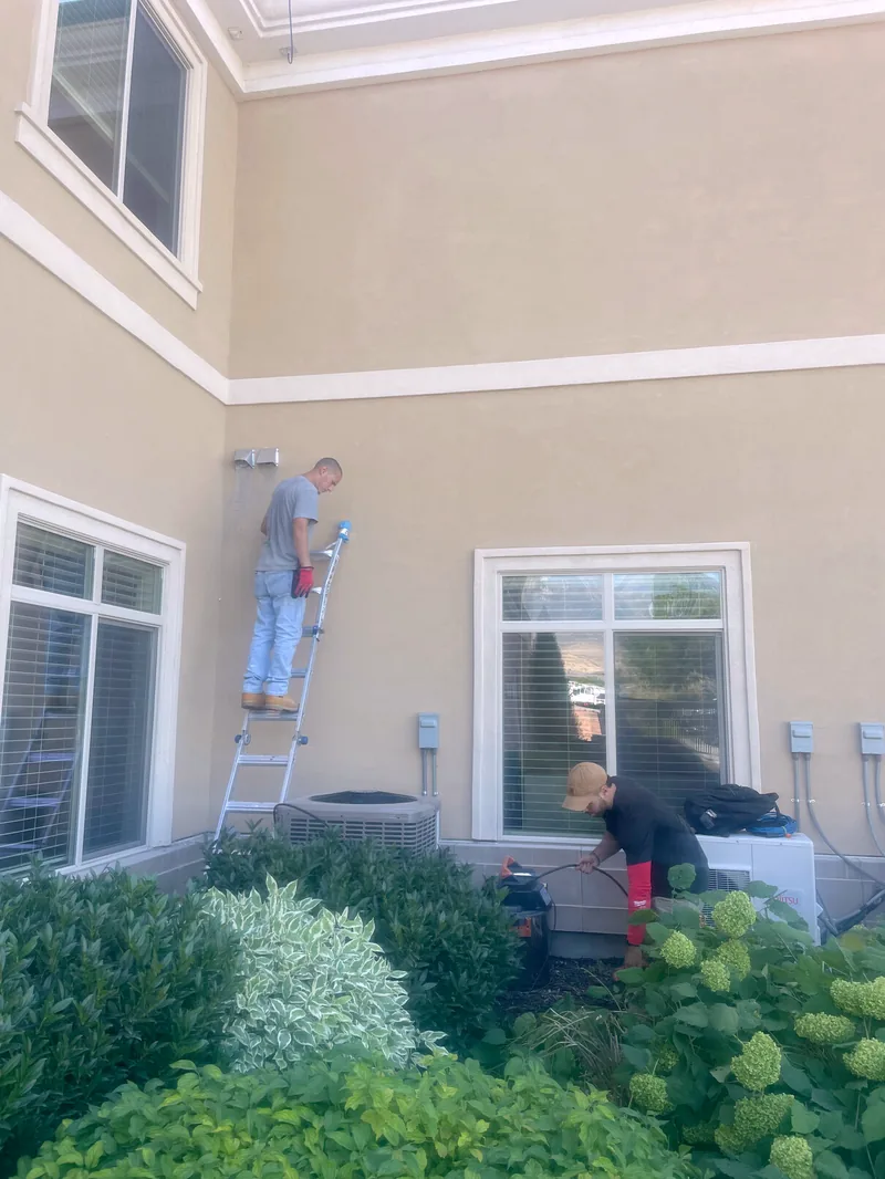 Technicians cleaning exterior dryer vents at Creekside Senior Living