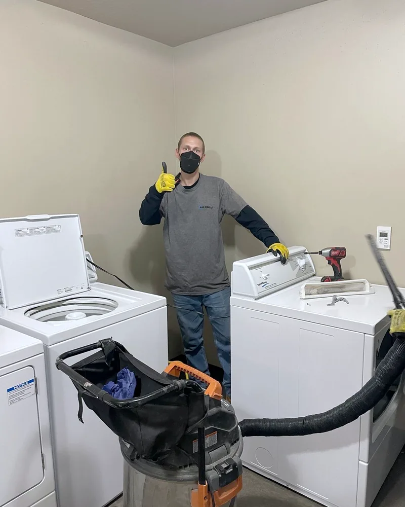 Technician servicing dryers in a laundry room