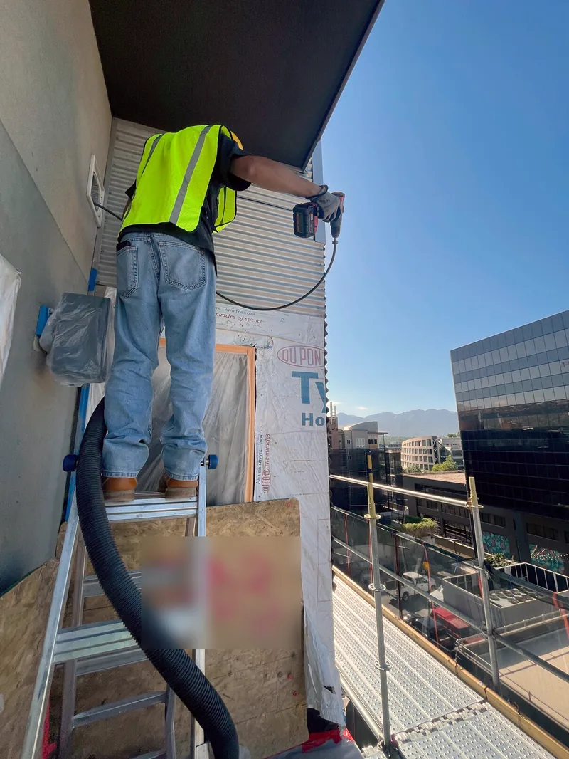 Technician cleaning a dryer vent from a balcony at The Metro Condominiums