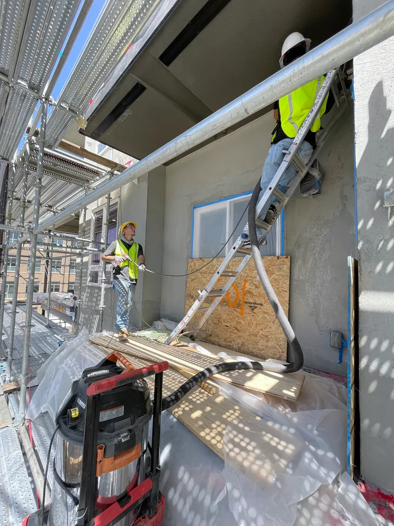 Technicians on scaffolding with vacuum equipment at The Metro Condominiums