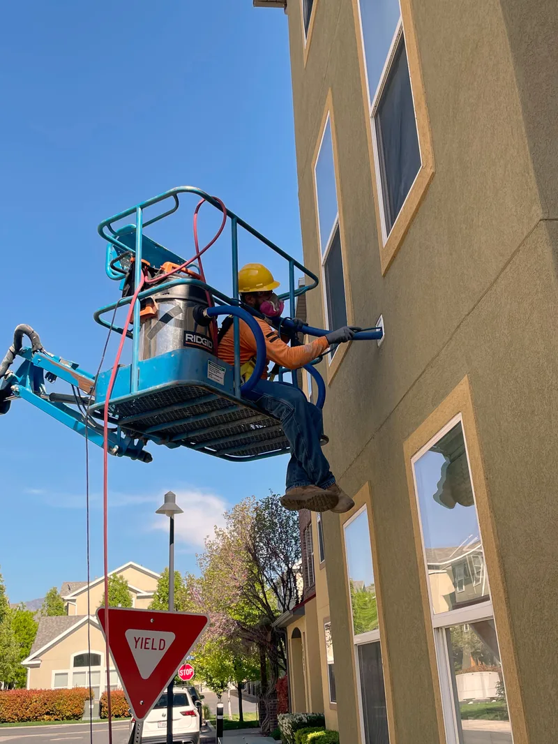 Technicians in a boom lift cleaning exterior dryer vents