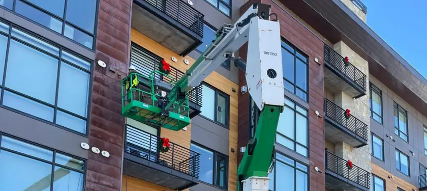 Air Pro UT technician in a boom lift cleaning dryer vent exhaust lines on a Salt Lake City apartment building
